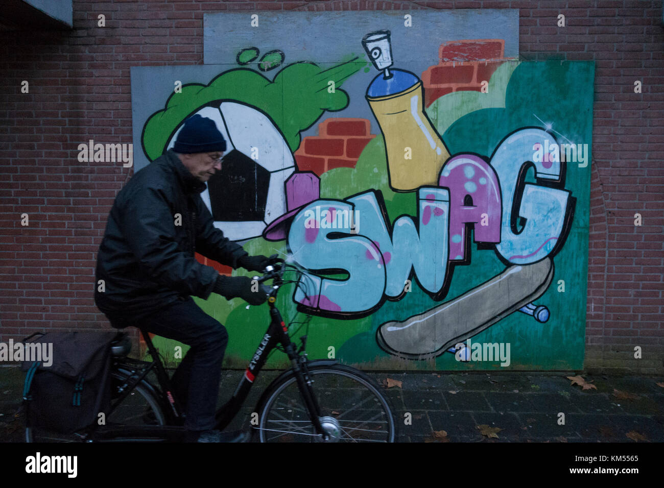 Man riding past graffiti wall Stock Photo