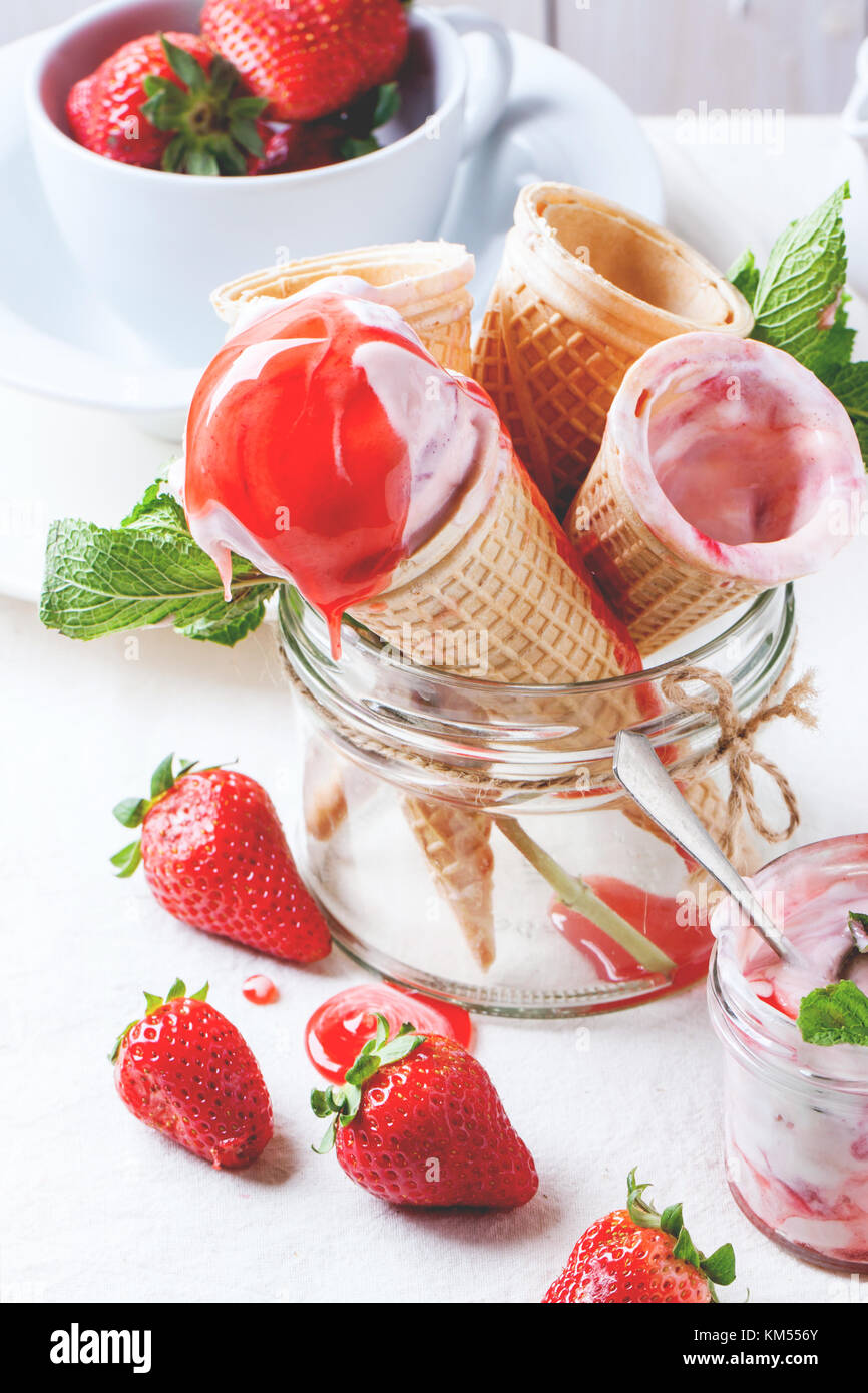 Wafer cones with strawberry ice cream with pouring syrup and fresh ...