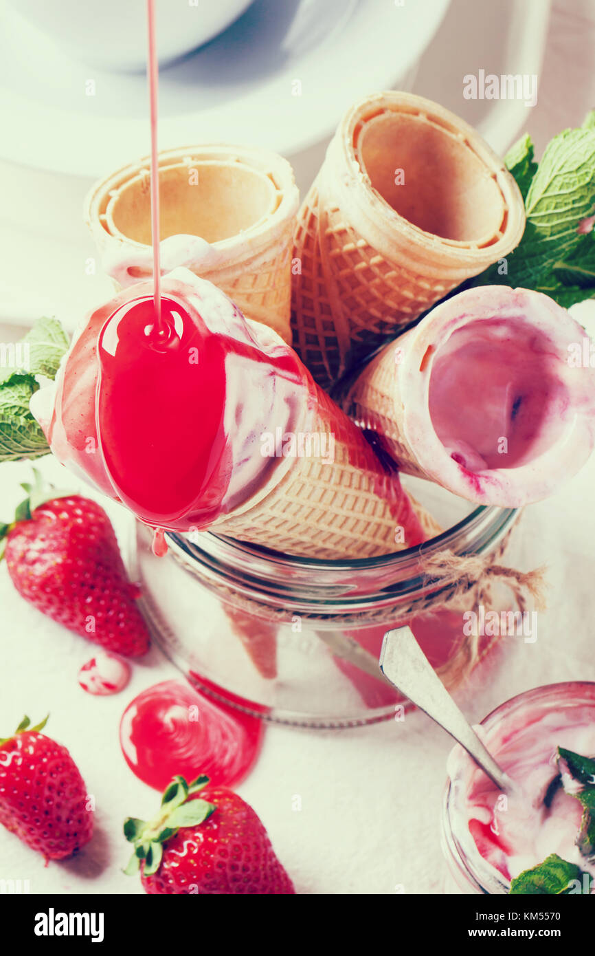 Wafer cones with strawberry ice cream with pouring syrup and fresh ...
