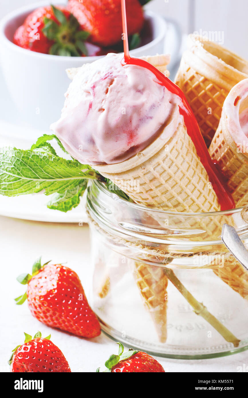 Wafer cones with strawberry ice cream with pouring syrup and fresh ...