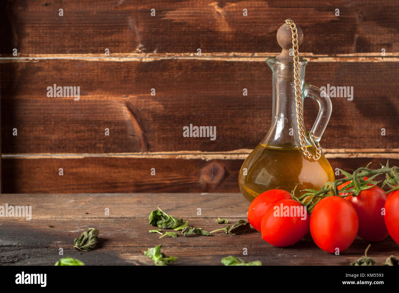 wet red cherry tomatoes on wooden table with olive oil in vintage glass ...