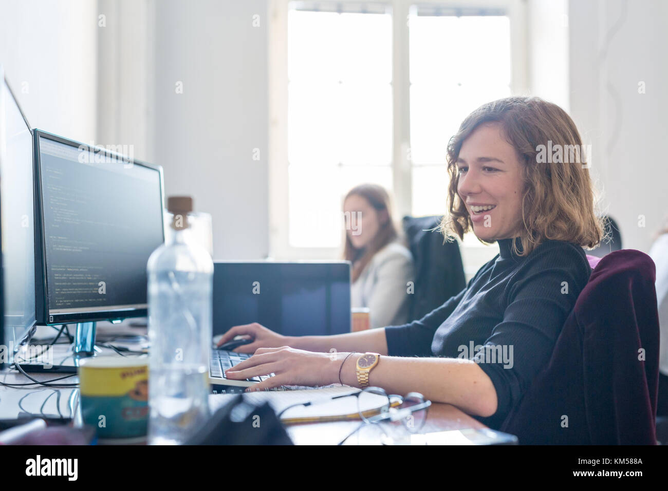 Yound devoted female software developers team working on desktop computer in IT statup company. Stock Photo