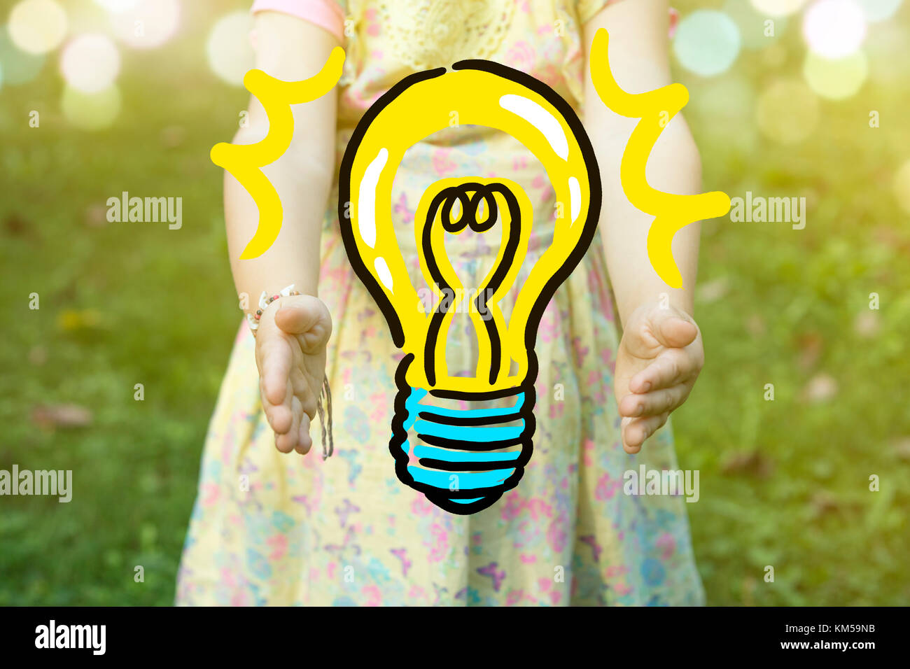 Child holding a light bulb drawing as idea concept, outdoors on a sunny day. Stock Photo