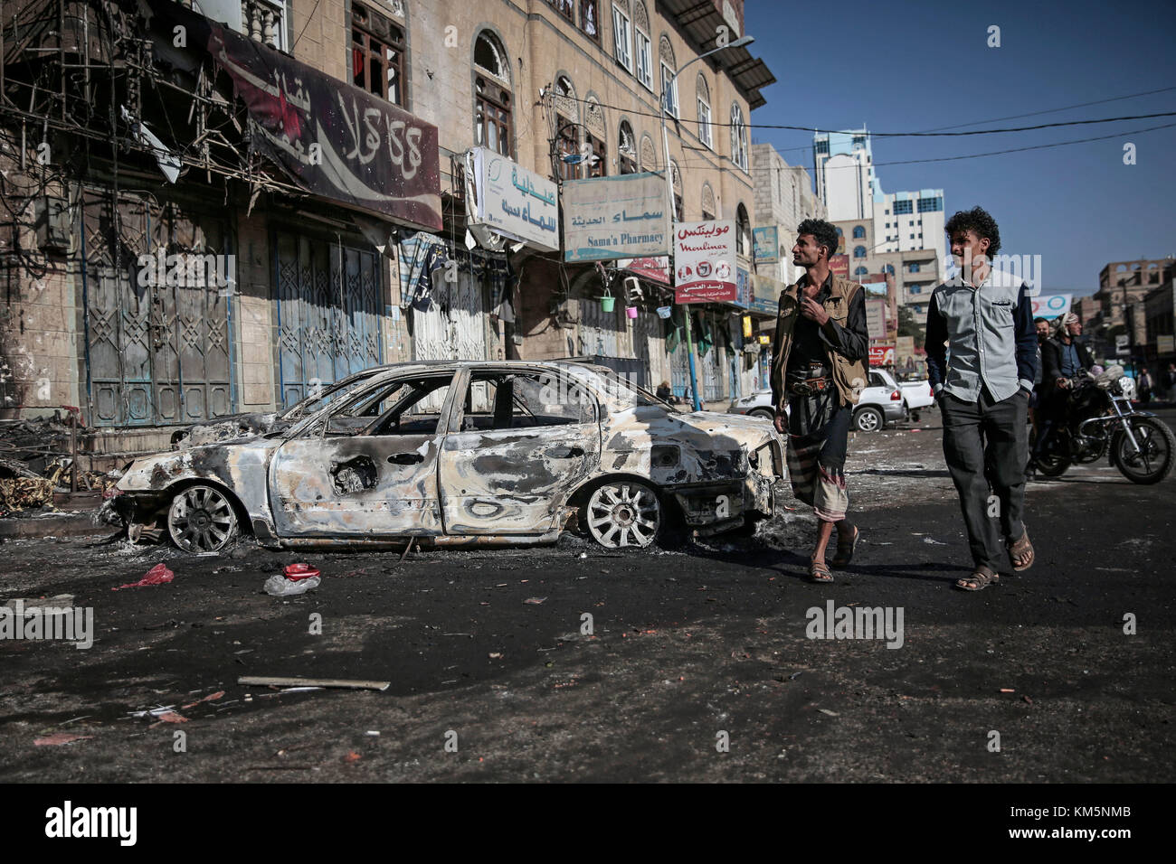Sanaa, Yemen. 05th Dec, 2017. Yemeni men walk past cars destroyed in clashes between Houthi fighters and forces loyal Yemen's former President Ali Abdullah Saleh in Sanaa, Yemen, 05 December 2017. Saleh was killed by Houthi rebels on Monday. Credit: Hani Al-Ansi/dpa/Alamy Live News Stock Photo