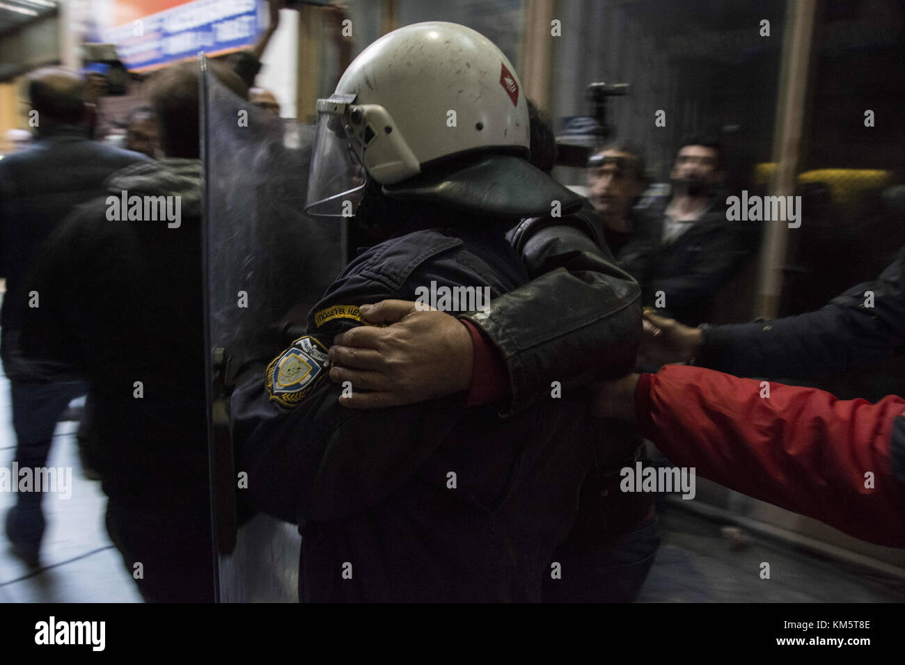 Athens, Greece. 5th Dec, 2017. Protesters escort a riot policeman to his unit after they broke the shutters of the Ministry of Labor and stormed it's entrance. Thousands, mostly members of PAME, the workers' union affiliated to the communist party, took to the streets to protest against a law, the government attempted to introduce, that would make it harder for unions to go on strike. Credit: Nikolas Georgiou/ZUMA Wire/Alamy Live News Stock Photo