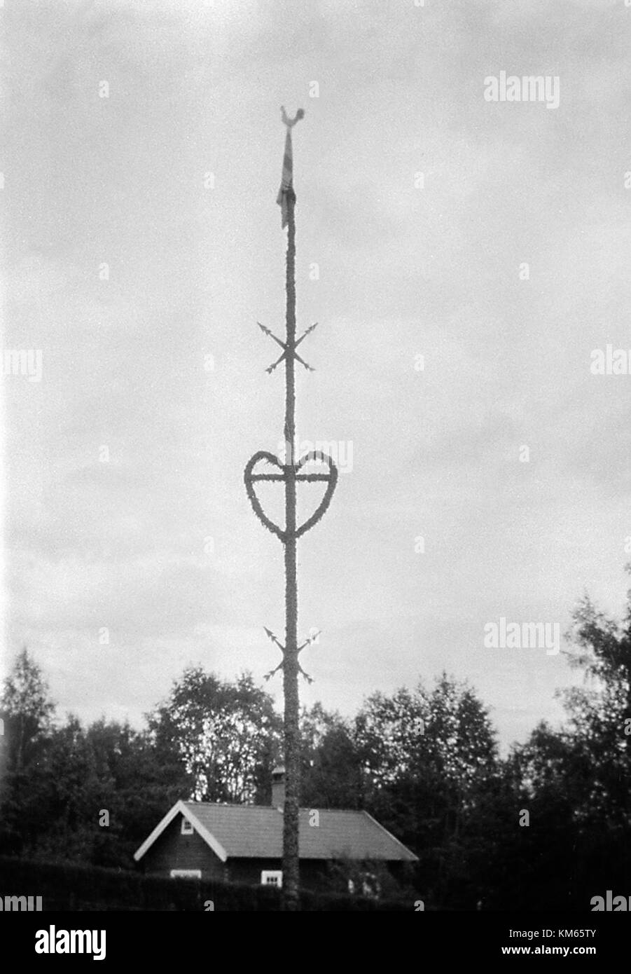 The maypole in Sjurberg village, Dalarna, Sweden, is an iconic symbol of Swedish midsummer traditions. This image captures the pole decorated with flowers, used in the village's annual celebration of the summer solstice. Stock Photo