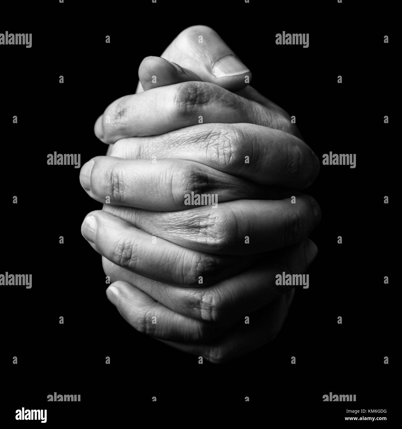 Low key, close up of hands of a faithful mature man praying, hands folded, interlaced fingers in worship to god. Isolated black background. religion Stock Photo