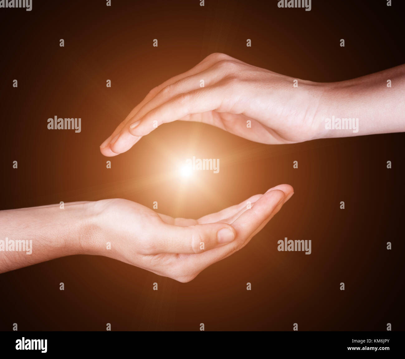 Woman hands protecting and containing bright, glowing, radiant, shining light. Emitting rays or beams expanding of center. Religion, divine, heavenly, Stock Photo
