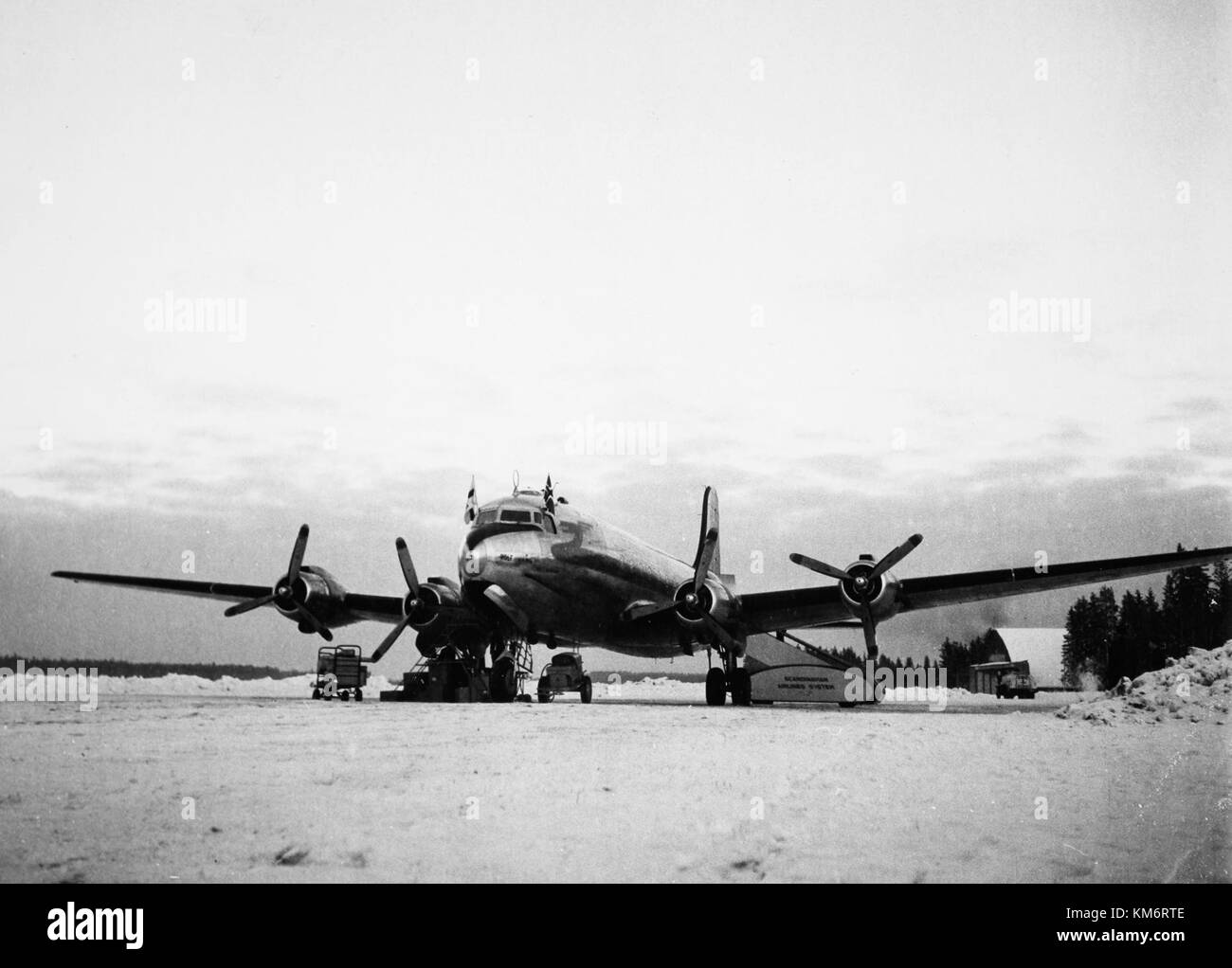 The SAS DC-4 aircraft, registered under the callsign Rolf Viking OY DFO, is shown on the ground at an airport in the 1950s during winter. This aircraft was part of the fleet operated by Scandinavian Airlines System (SAS) during the early years of commercial air travel. Stock Photo