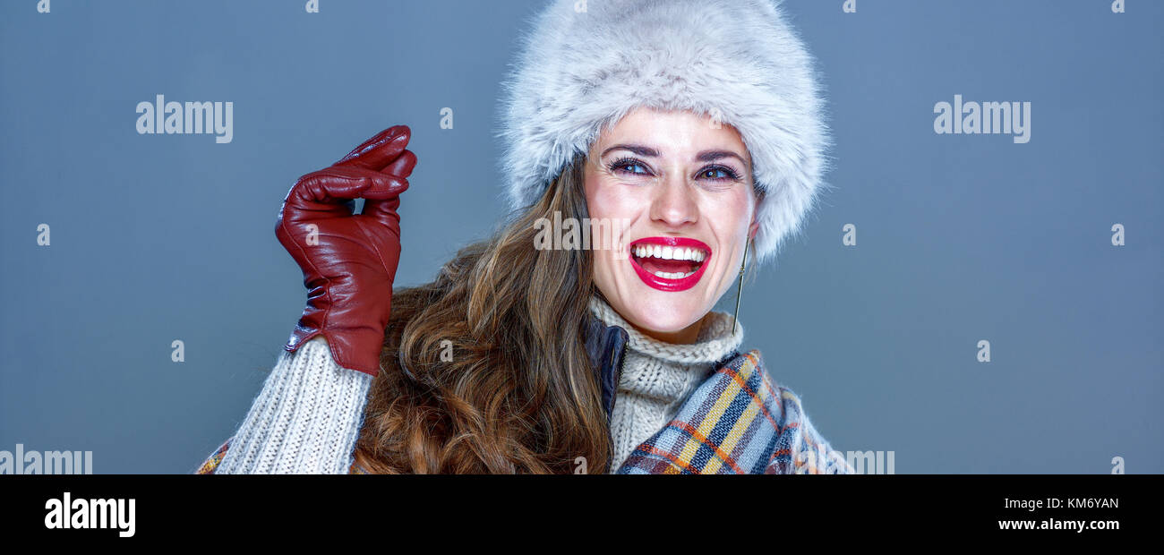 Winter things. Portrait of happy trendy woman in fur hat isolated on cold blue background snapping fingers and looking on copy space Stock Photo