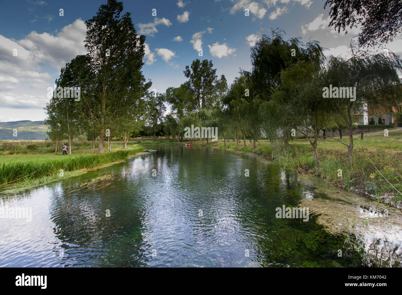 River Gacka with willow trees and a small red rowingbiat near Otocac, Croatia Stock Photo