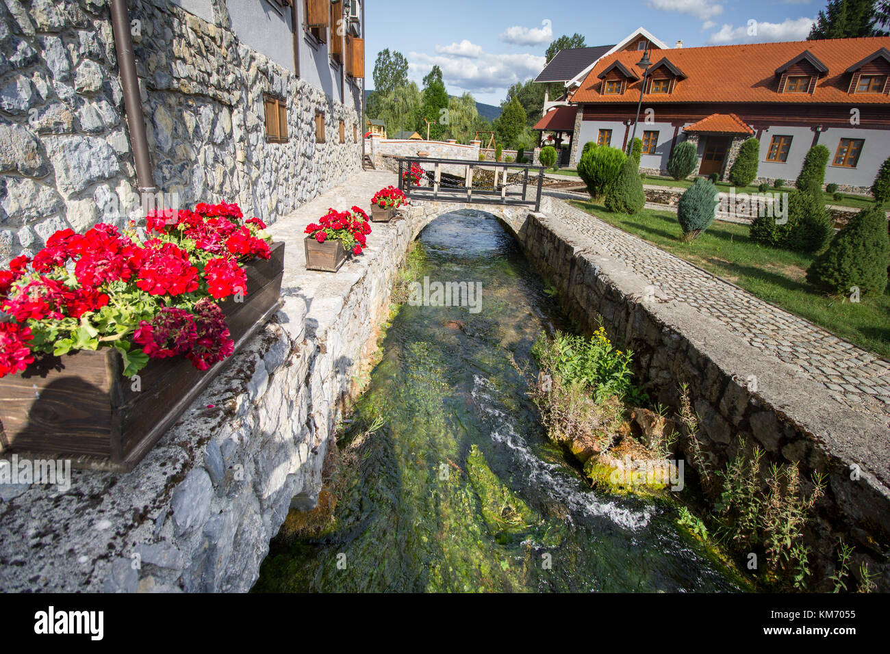 Hotel Gacka in Lika County near Otocac, Croatia.   A water channel with fast flowing water from the spring passes down the side of the hotel Stock Photo