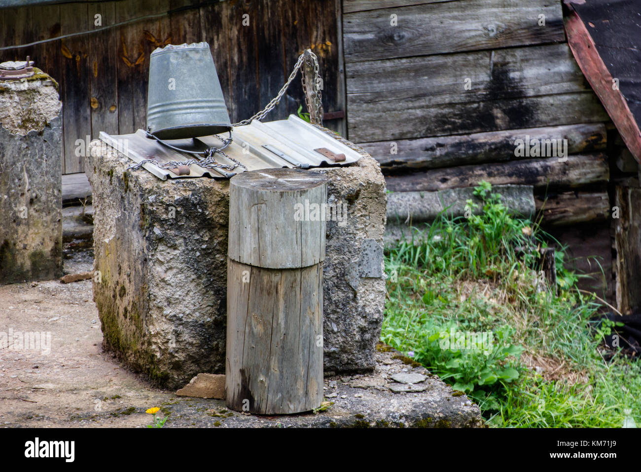 An old well with bucket and chain and a couple of old tree stumps in Croatia Stock Photo