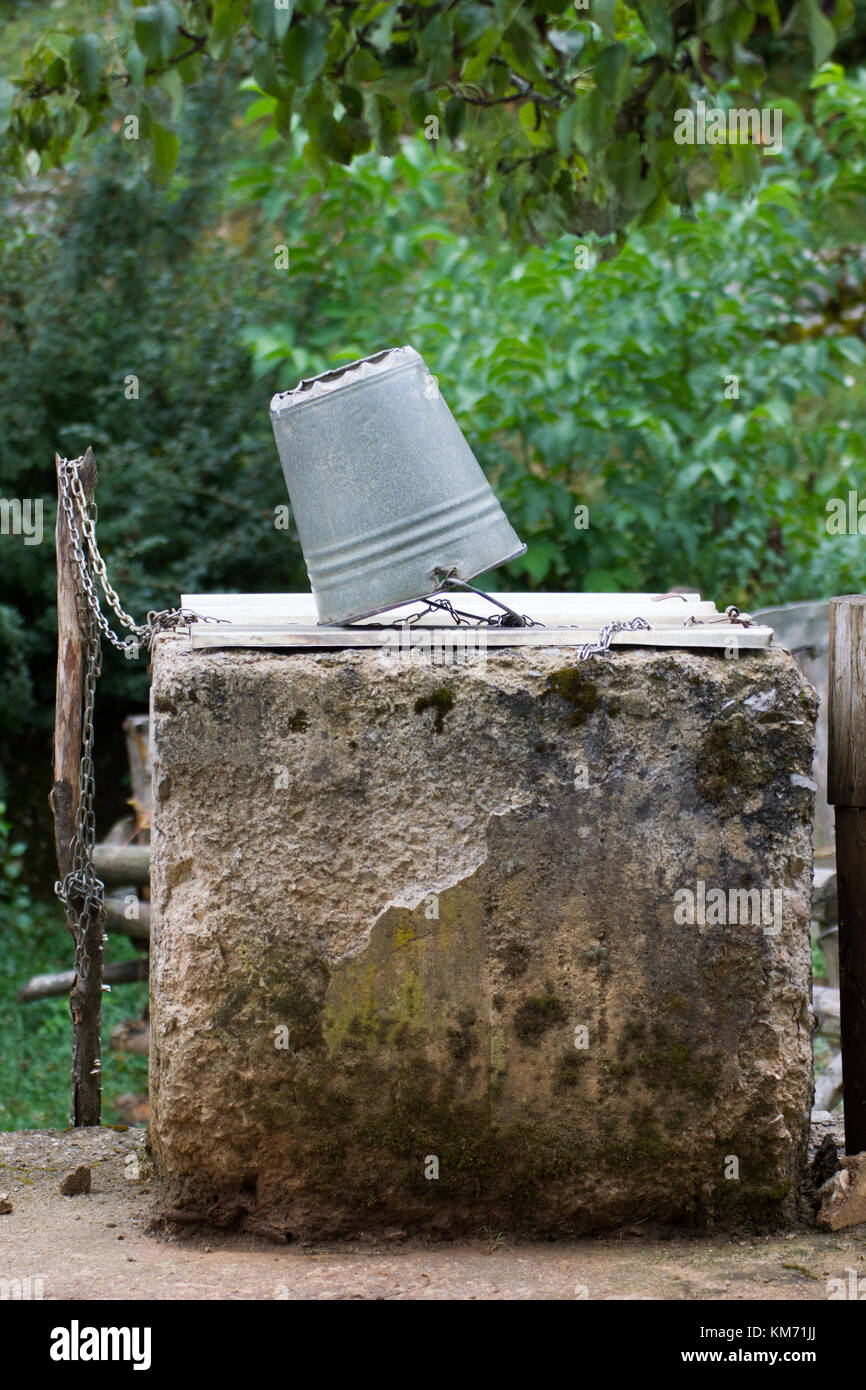 Chain and galvanised bucket on top of an old concrete well in Croatia Stock Photo