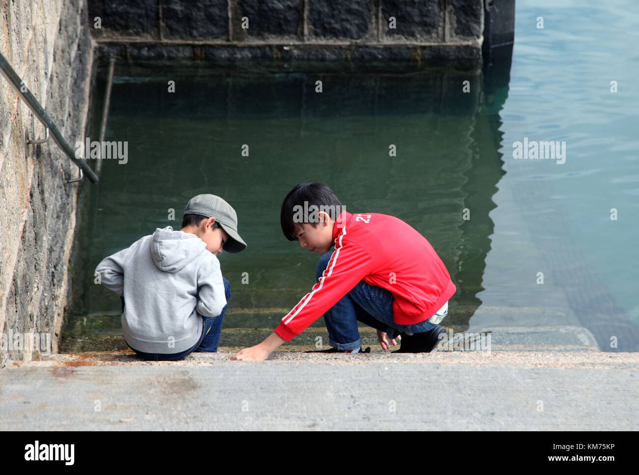 2 young boys playing near the water in a harbor Stock Photo