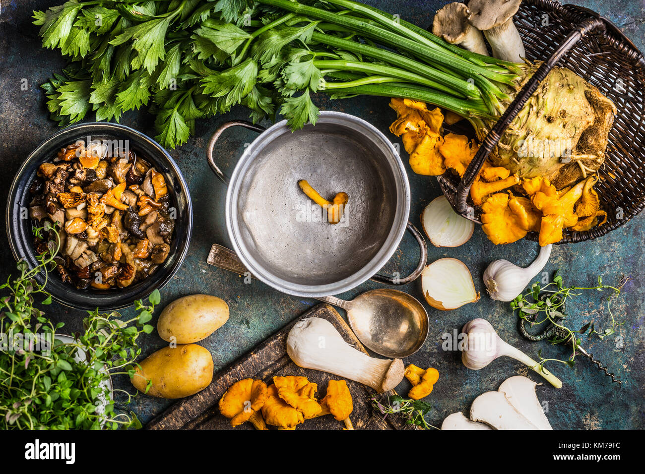 Forest Mushrooms cooking preparation on rustic kitchen table with empty cooking pot and vegetables, top view. Autumn cooking concept Stock Photo