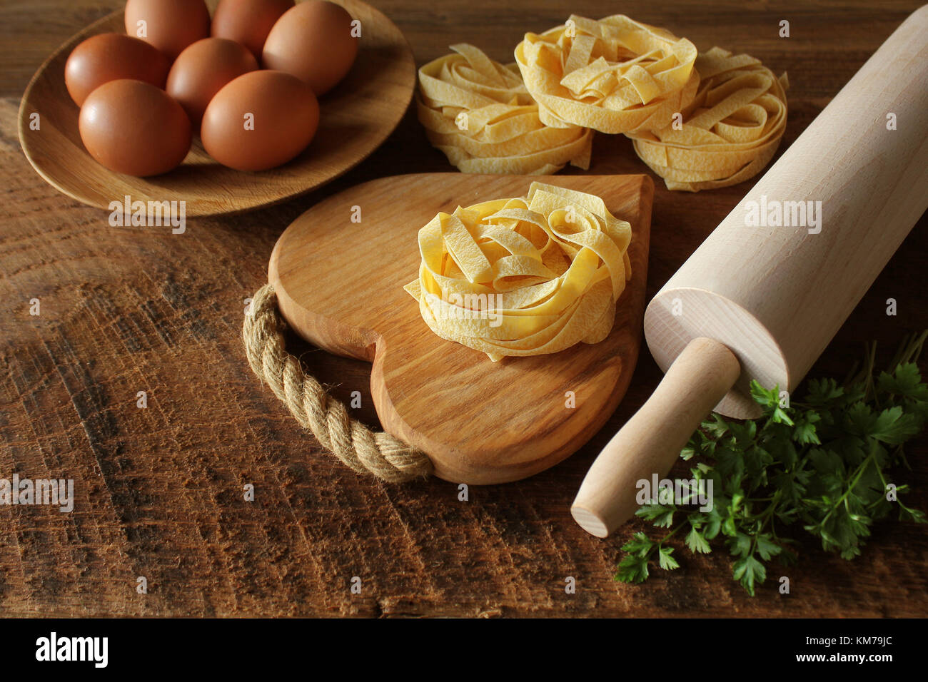 Raw italian pasta tagliatelle on wooden board and rolling pin on rustic