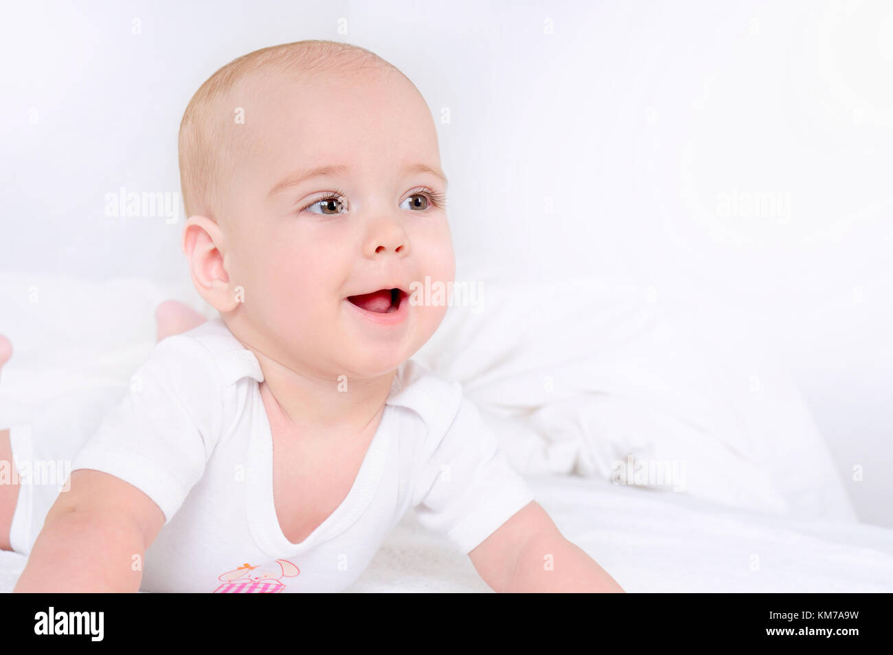 Happy child lie on white bed and smile. Close up portrait. Happy ...