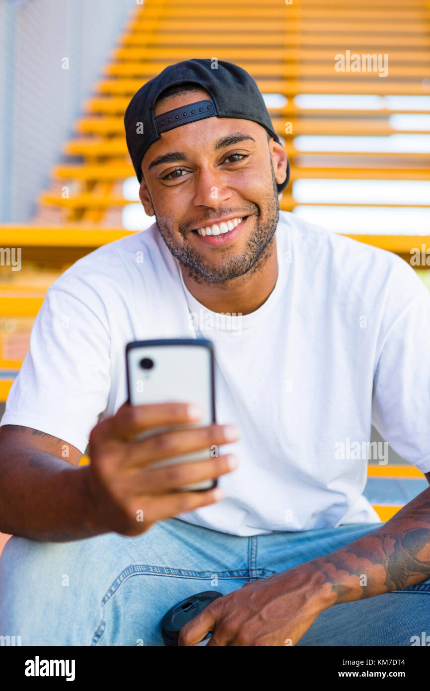 Portrait of a young man sitting on stairs using smartphone Stock Photo ...