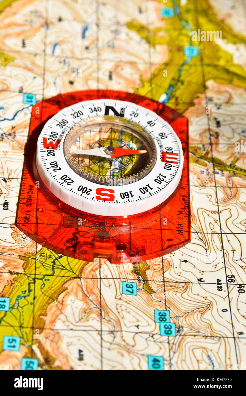 Don't get lost in the journey! The magnetic compass lies on a topographic map. Stock Photo