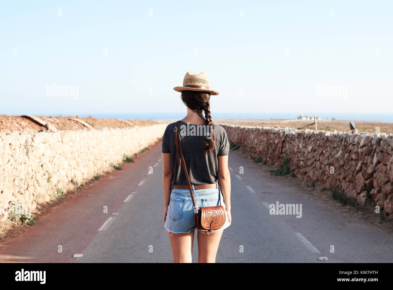 Menorca, Spain, solo traveler view from behind in a empty road to a lighthouse, solo traveler Stock Photo