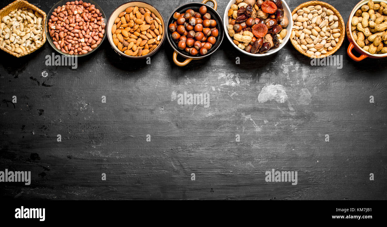 Various nuts in bowls. On a black chalkboard. Stock Photo