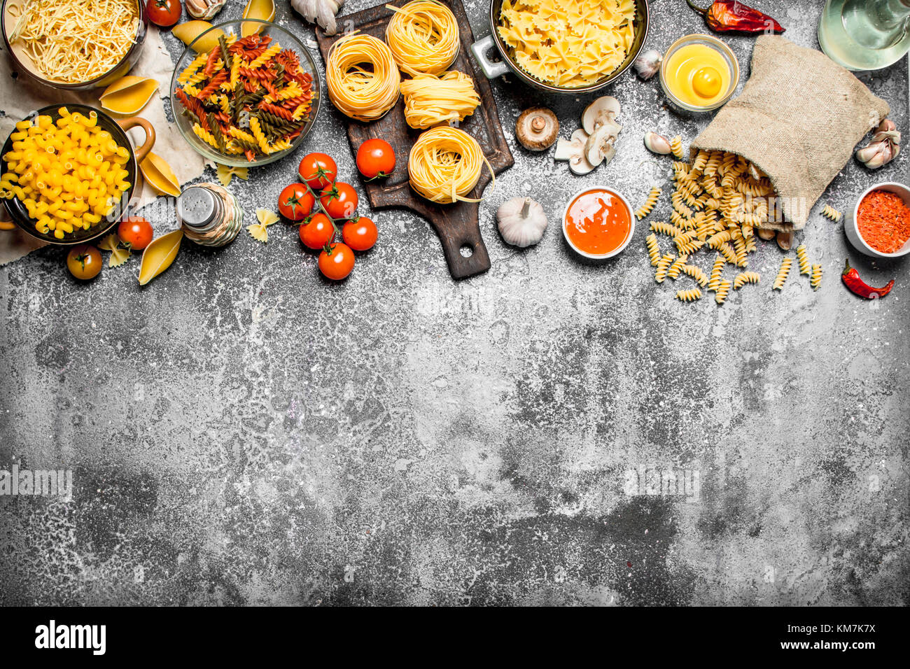 Pasta background. Pasta with sauces, vegetables and olive oil.On rustic ...
