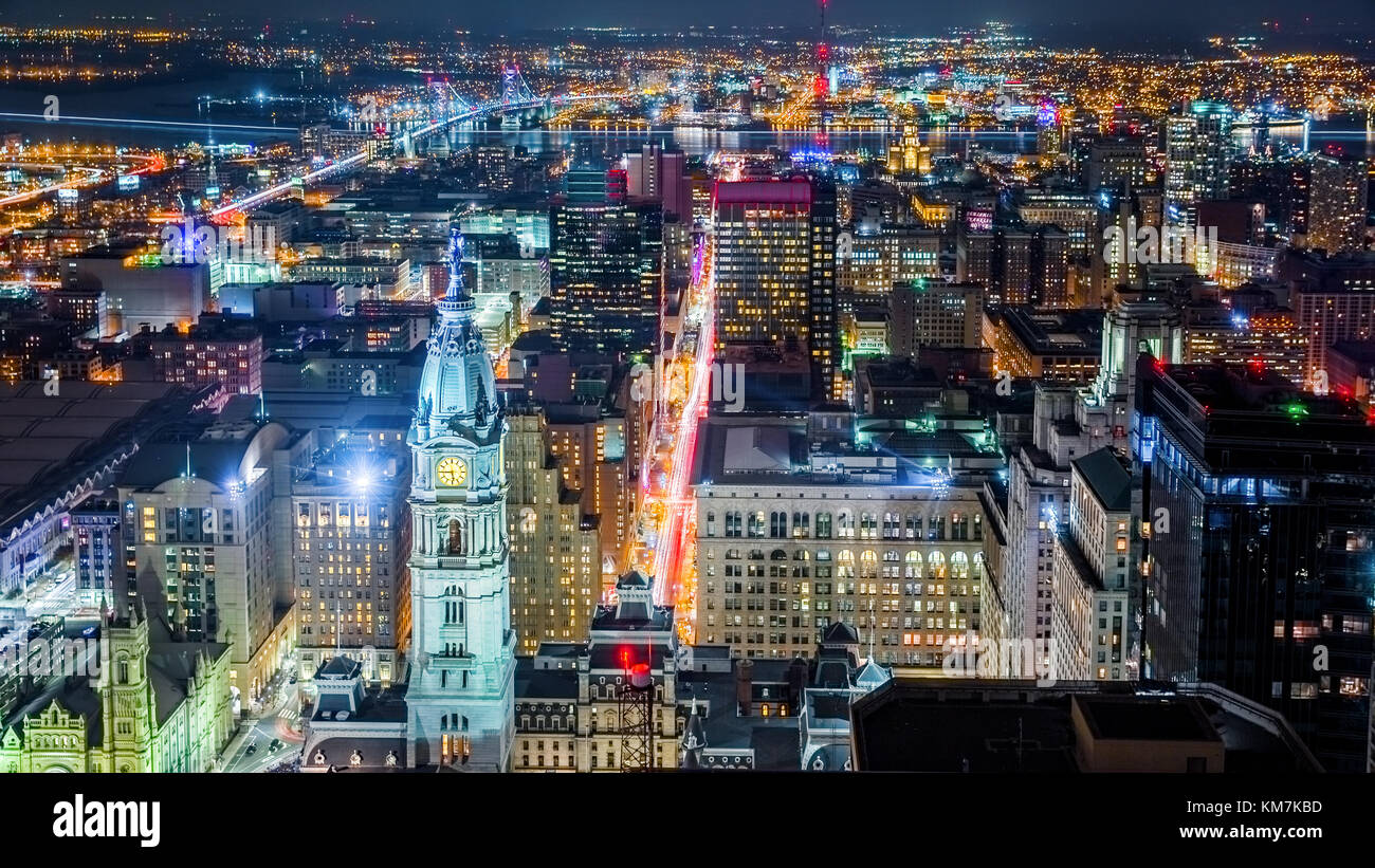 Aerial Philadelphia cityscape by night with the City Hall tower in the foreground and Ben Franklin bridge spanning Delaware river in the back Stock Photo