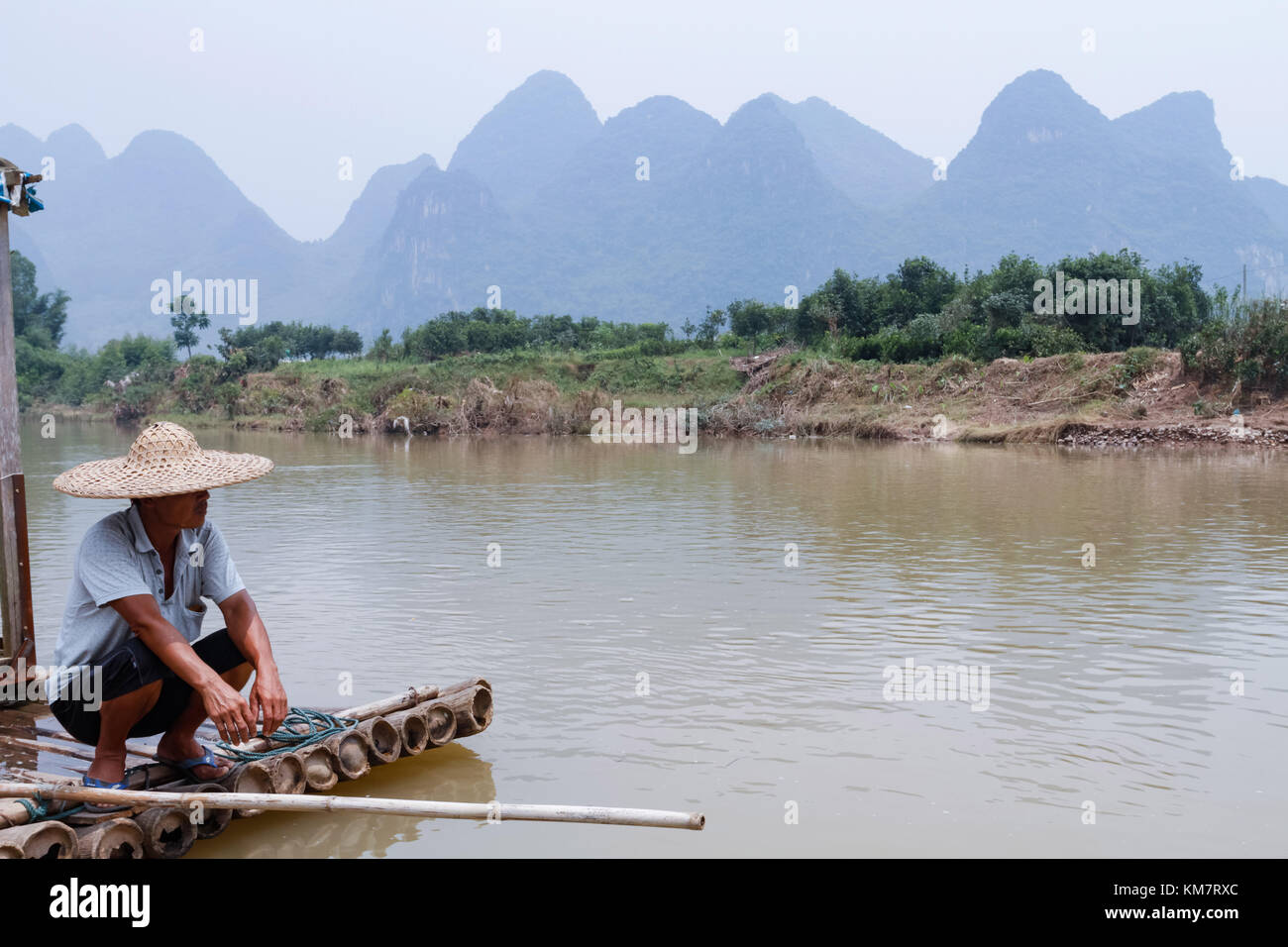Boat operator resting on bamboo raft at Li River in China. Stock Photo