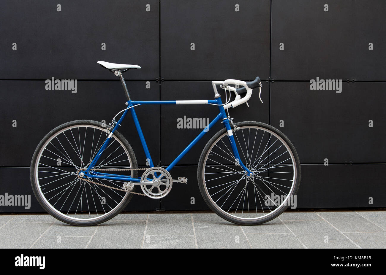 Vintage blue and white city bicycle on a black wall. Road bicycle Stock Photo