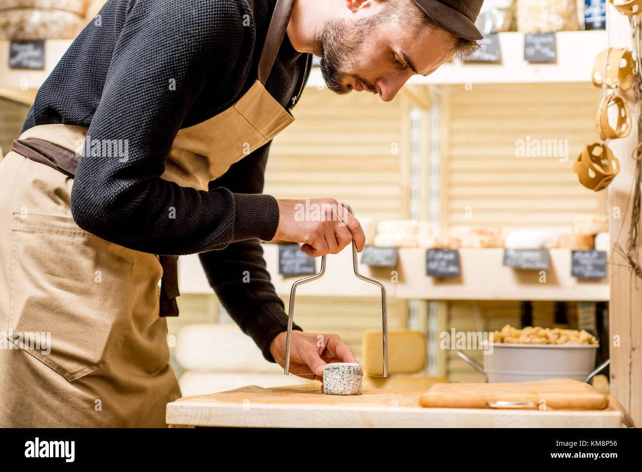 Portrait of a handsome salesman in uniform cutting cheese in front of
