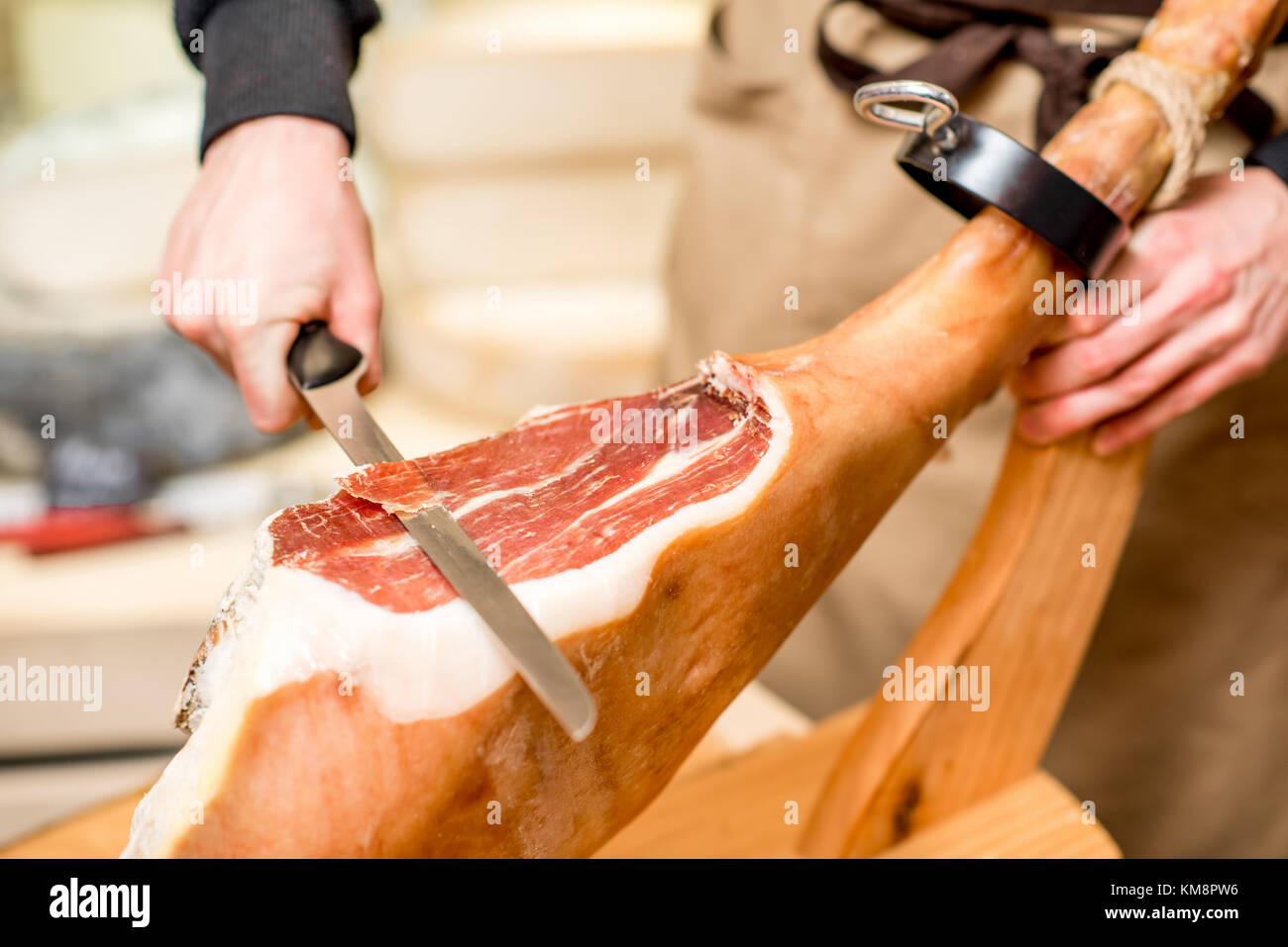 Cutting with long knife prosciutto leg in the food store Stock Photo