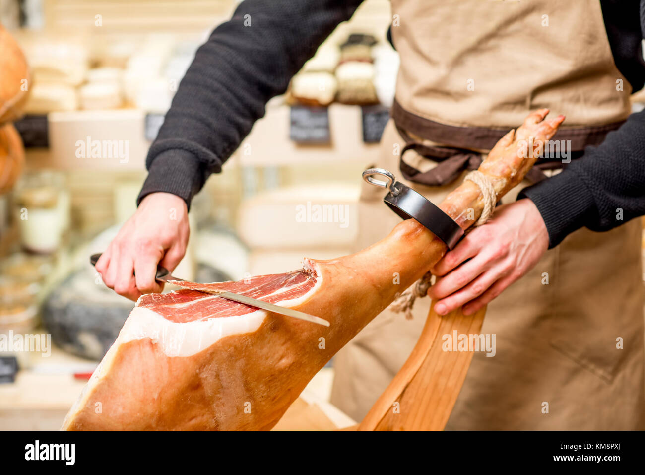 Cutting with long knife prosciutto leg in the food store Stock Photo