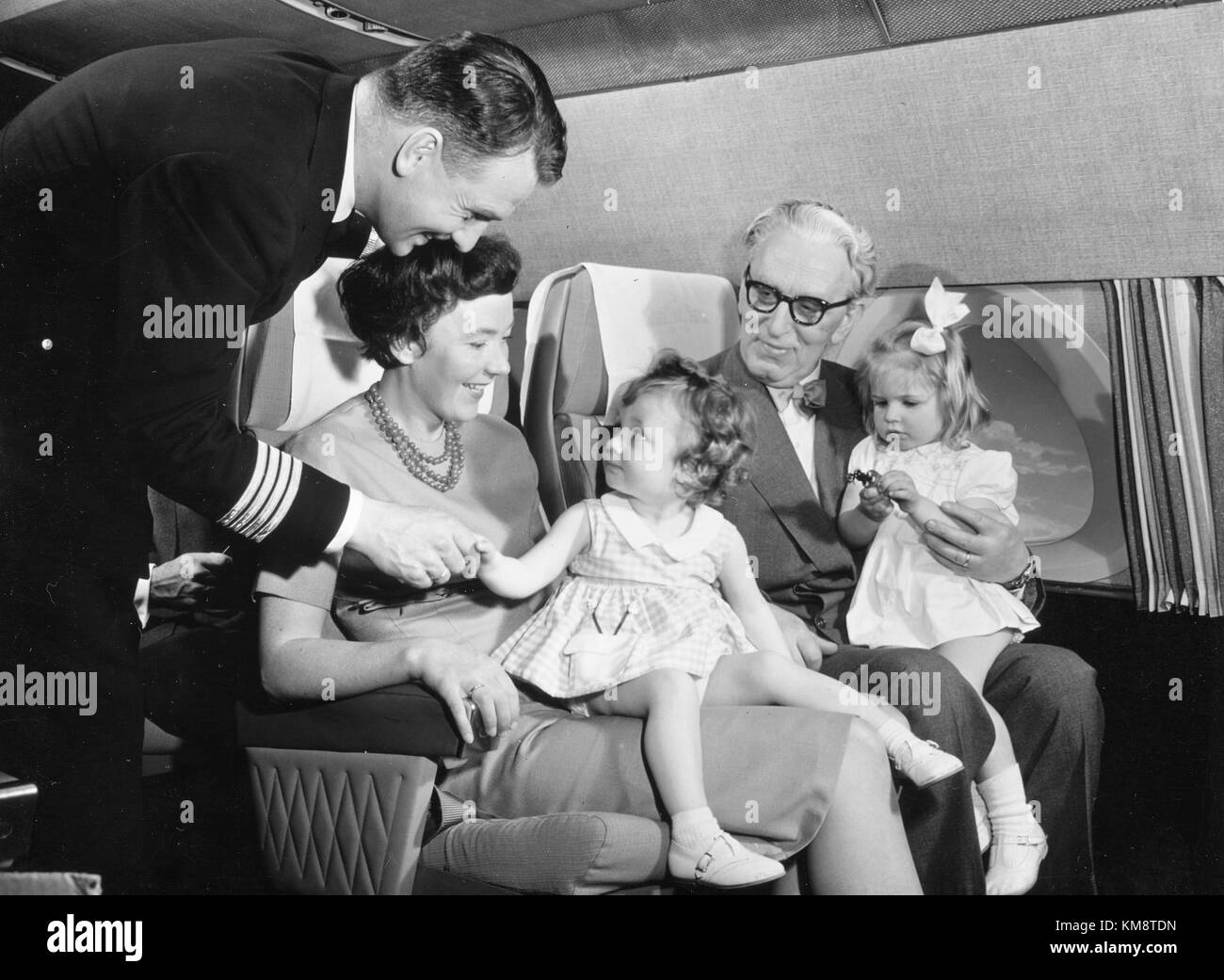 SAS DC 8 33 Interior of cabin with passengers, elderly people and children talking to captian of the aircraft. Service on board, cabin and seats. New decor Stock Photo