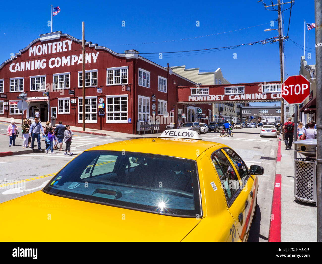 AMERICANA CANNERY ROW TOURISM Monterey Canning Company building flying stars & stripes American Flag , Cannery Row with traditional yellow city taxi cab in foreground Monterey California USA Stock Photo