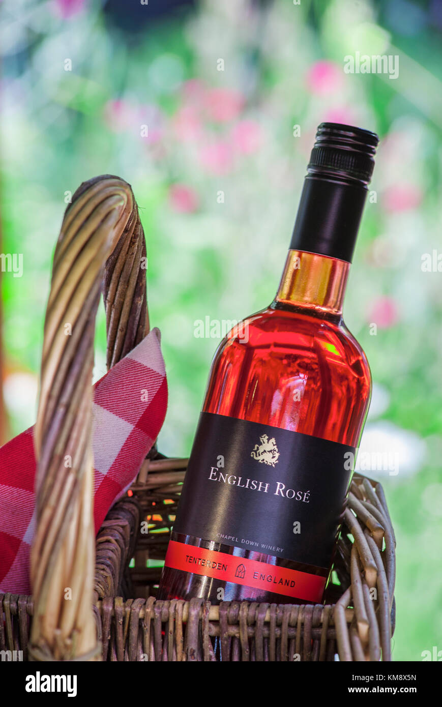 English Rosé wine bottle and wicker bottle carrier basket in alfresco floral garden picnic situation Stock Photo