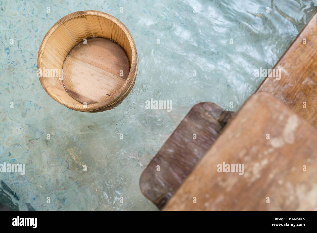 japanese style hot springs with wooden barrel scoop floating on water and water flowing. Stock Photo