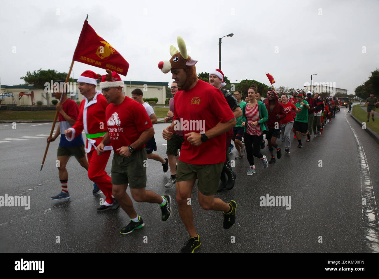 marines and sailors with medical logistics company, 3rd supply battalion, combat logistics regiment 35, run across base during the 7th annual jingle bell run hosted by marine corps community services at camp kinser, okinawa, japan dec. 1, 2017. the event featured a costumed fun run, christmas caroling, games and prizes for marines and sailors, who attended to celebrate the holiday season. Stock Photo