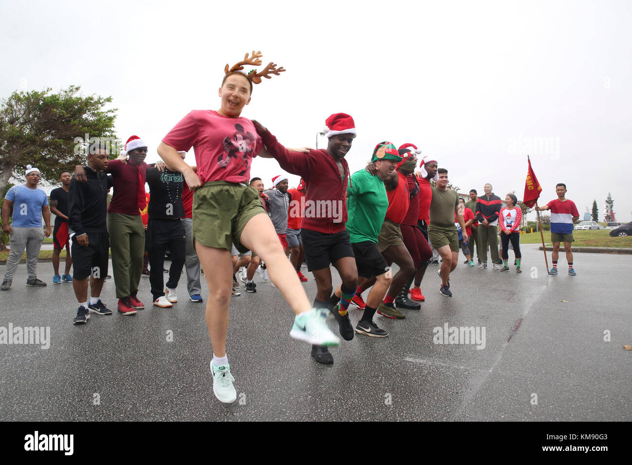 marines and sailors with medical logistics company and supply company, 3rd supply battalion, combat logistics regiment 35, dance and sing christmas carols during the 7th annual jingle bell run hosted by marine corps community services at camp kinser, okinawa, japan dec. 1, 2017. the event featured a costumed fun run, christmas caroling, games and prizes for marines and sailors, who attended to celebrate the holiday season. Stock Photo