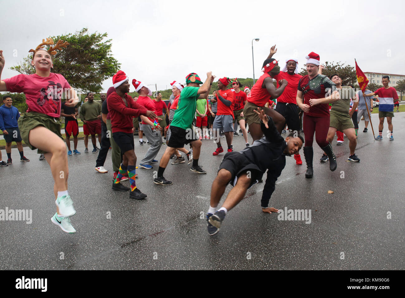 marines and sailors with medical logistics company and supply company, 3rd supply battalion, combat logistics regiment 35, dance and sing christmas carols during the 7th annual jingle bell run hosted by marine corps community services at camp kinser, okinawa, japan dec. 1, 2017. the event featured a costumed fun run, christmas caroling, games and prizes for marines and sailors, who attended to celebrate the holiday season. Stock Photo