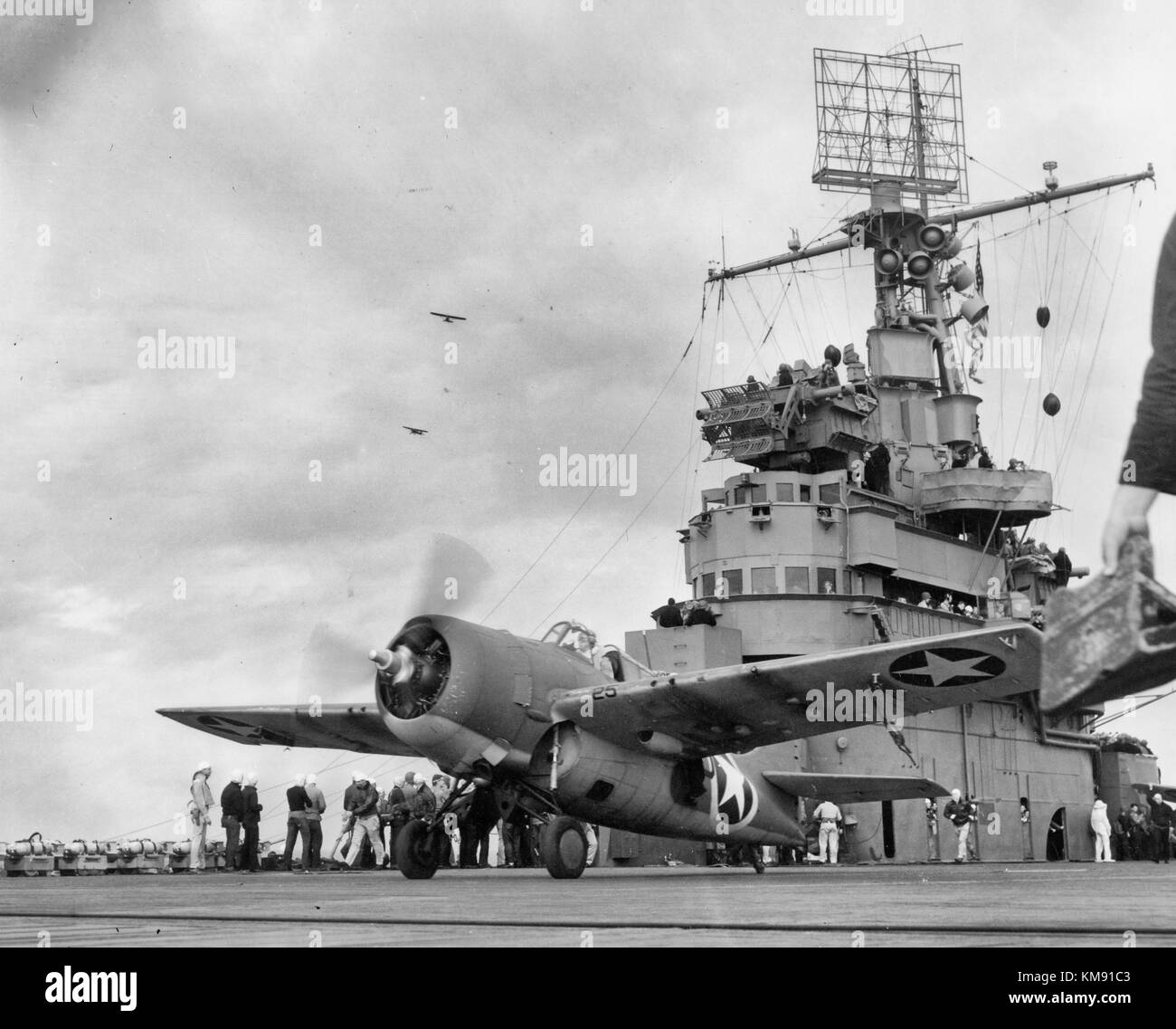 A Grumman F4F-4 Wildcat fighter taking off from USS Ranger (CV-4) to attack targets ashore during the invasion of Morocco, circa 8 November 1942. Note: Army observation planes in the left middle distance; Loudspeakers and radar antenna on Ranger's mast. Operation Torch Stock Photo