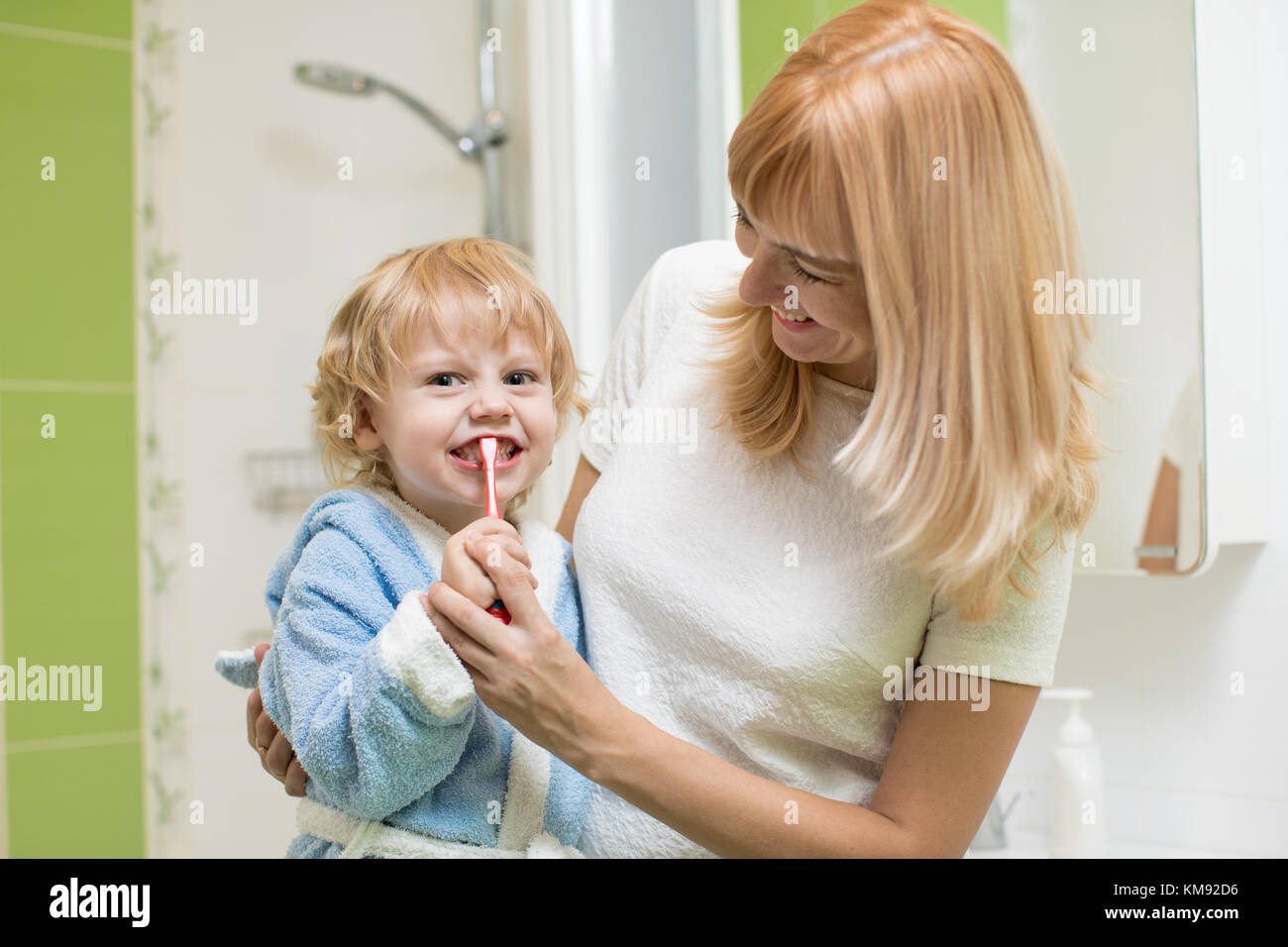 Child oral care. Mom is helping kid brush his teeth. Stock Photo