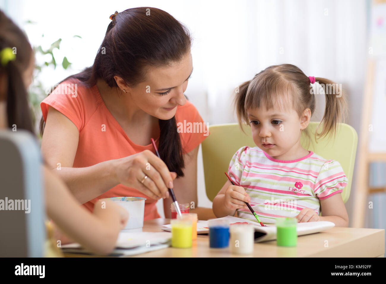 woman teaches kids painting at kindergarten or playschool Stock Photo