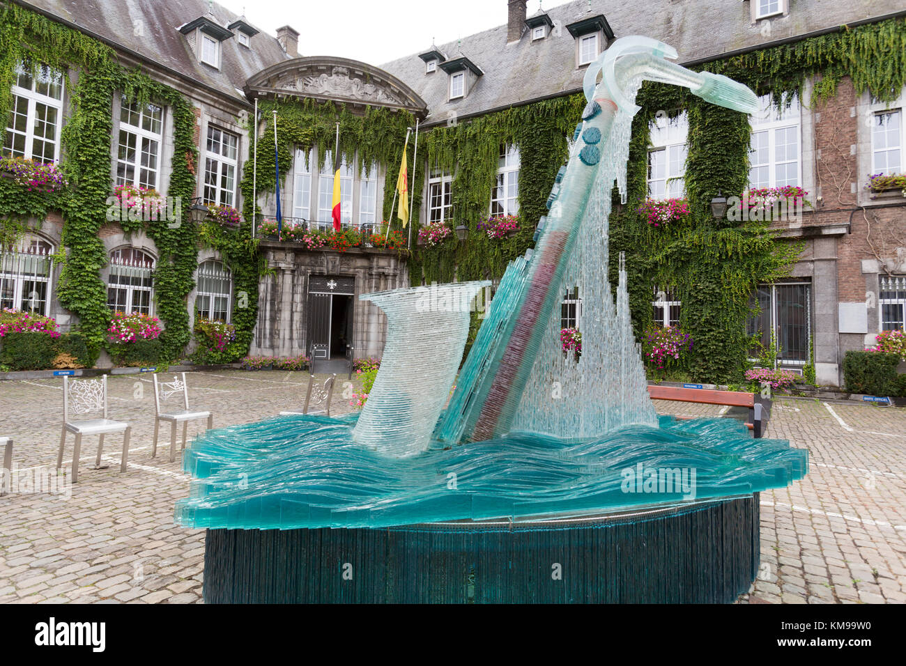 Town of Dinant, Belgium. Picturesque view of the Bernard Tirtiaux glass saxophone fountain sculpture, with Dinant Town Hall in the background. Stock Photo