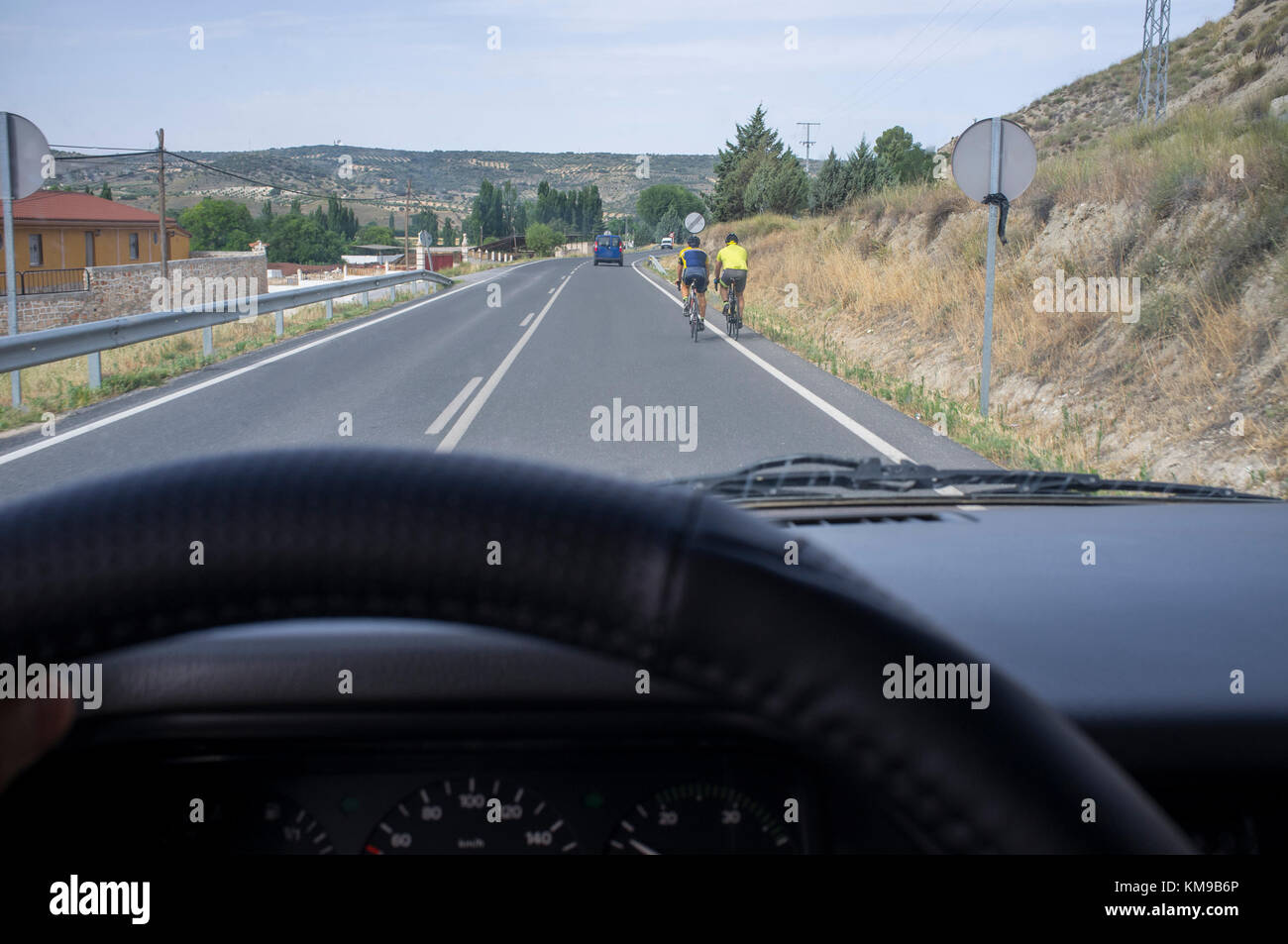 Driving slowly behind cyclists at local road. View from the inside of the car Stock Photo