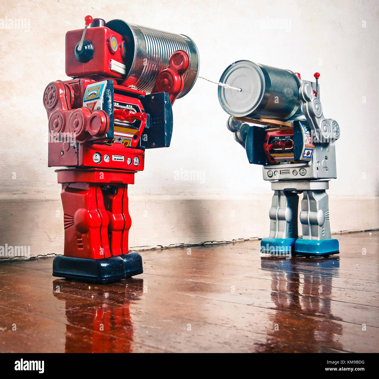 Two retro Robots toys talking on tin can phones on an old wooden floor  Stock Photo - Alamy