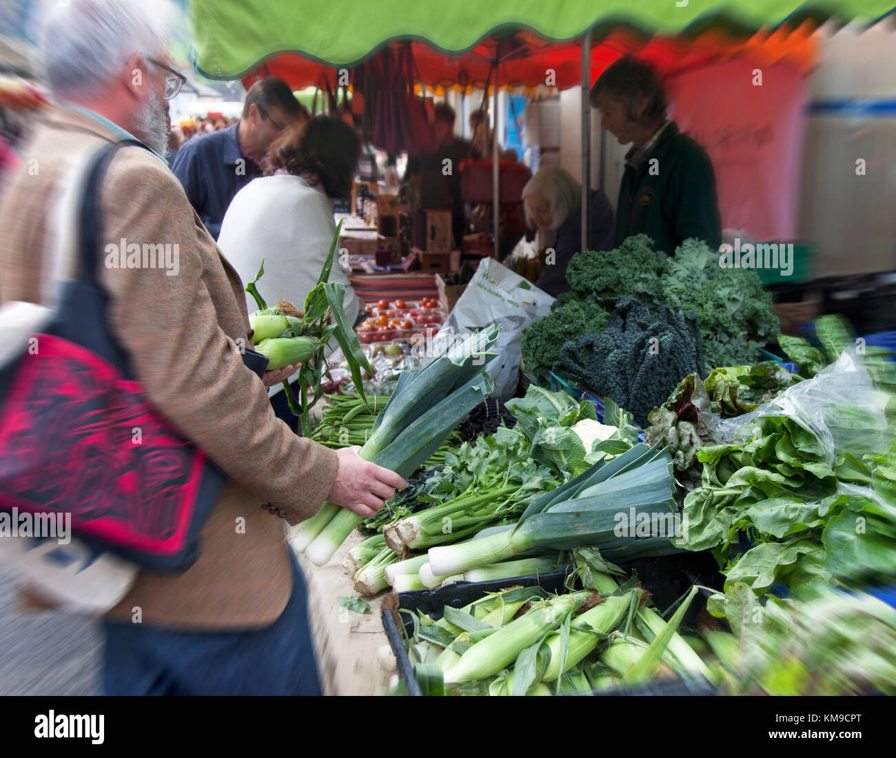 A man buys leeks and sweetcorn from a stall at the awatrd winning Stroud Farmers Market in Gloucestershire, UK Stock Photo