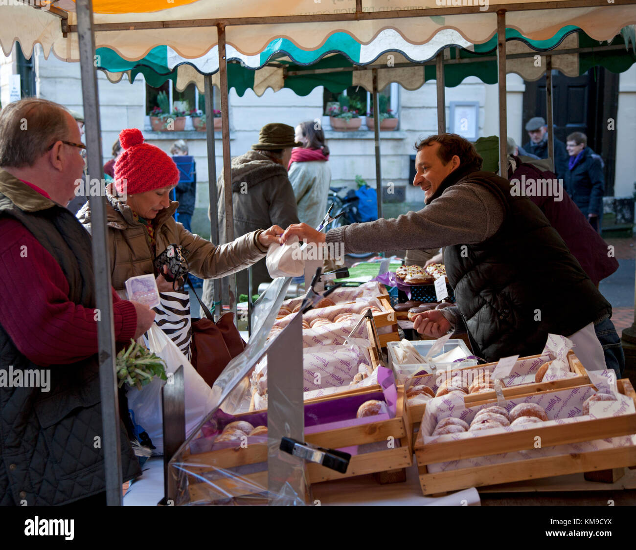 A woman shopper buying donuts at an artisan bakers market stall at the award winning Farmers Market in Stroud, Gloucestershire, UK Stock Photo