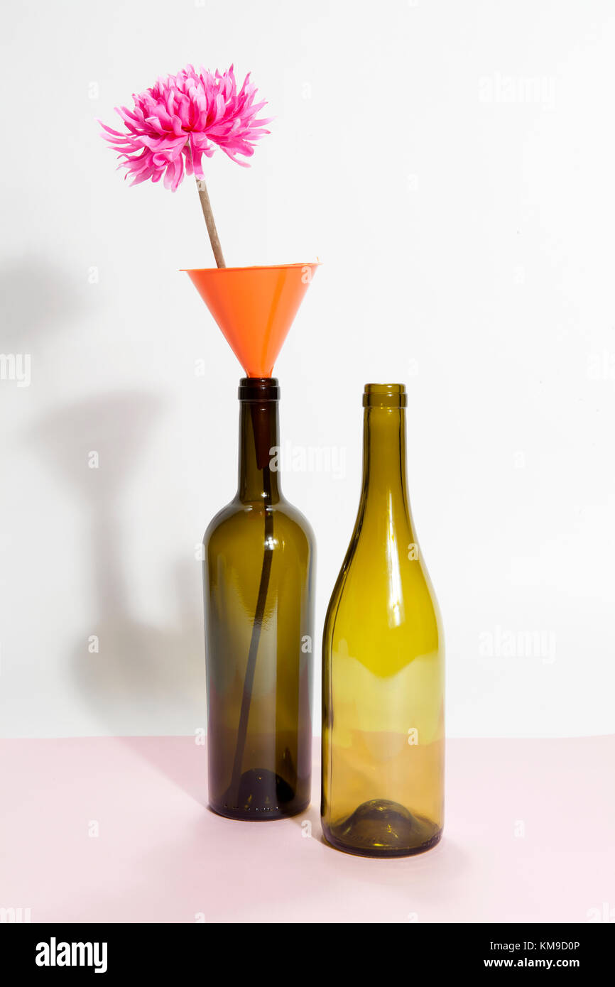 Two brown glass bottles isolated on a bicolor background. a funnel with pink flower inside. Minimal wacky color still life photography Stock Photo