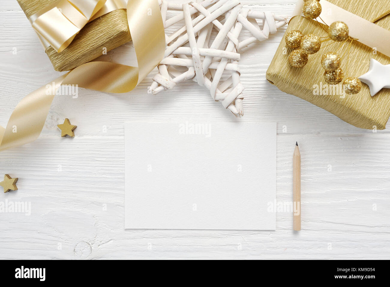 Mockup Christmas greeting card with gold gift ribbon, flatlay on a white wooden background, with place for your text Stock Photo